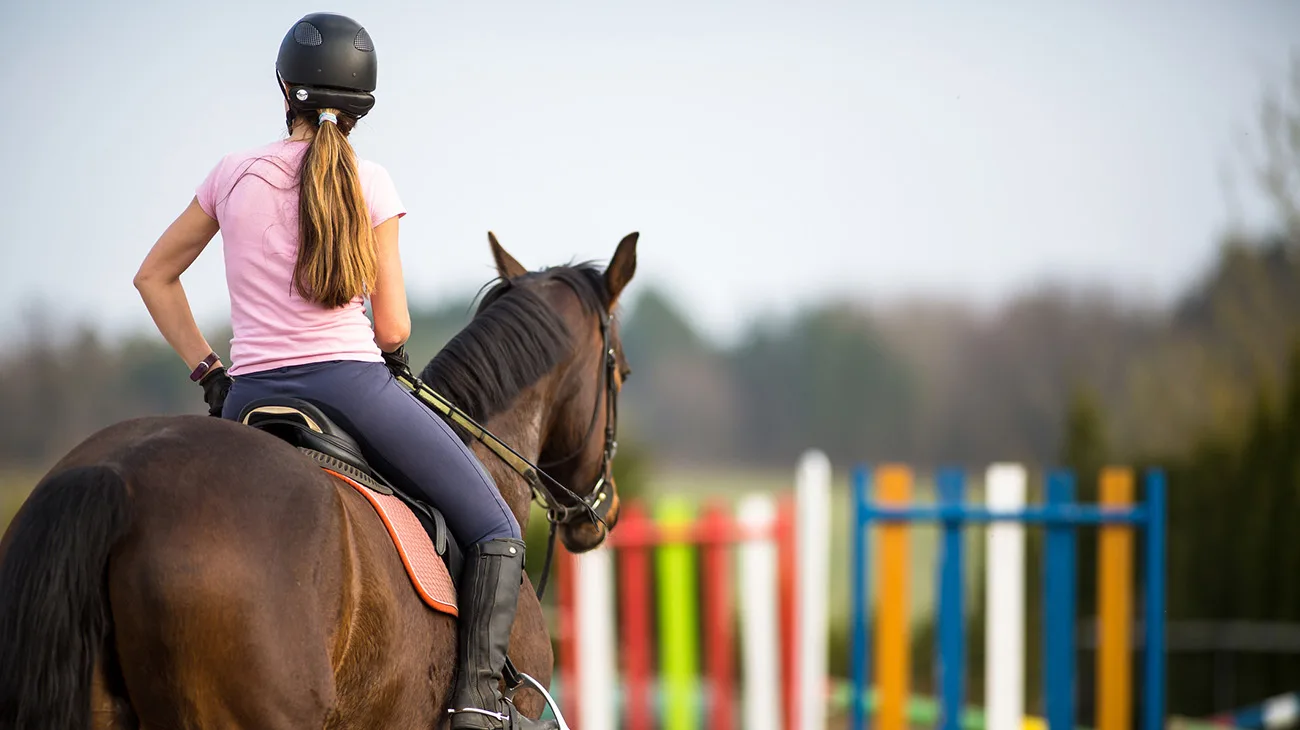 Young woman show jumping with horse on a Equestrian arena during a competition or training